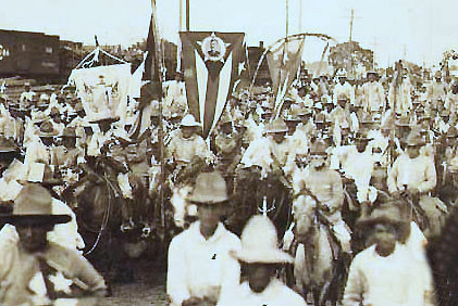 Las fuerzas del General Gómez entrando en uno de los pueblos de Camagüey al ritmo de La Chambelona con banderas y retratos 